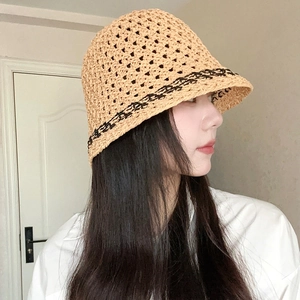 Detail side view of a khaki crochet bucket hat with black wavy trim on a female model