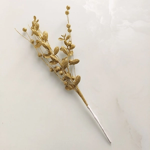 Close-up of golden glittered Christmas berry branch with shiny finish on white marble
