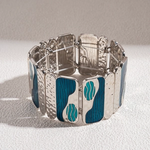 Macro detail of wide stretch bracelet with blue enamel waves and hammered metal texture