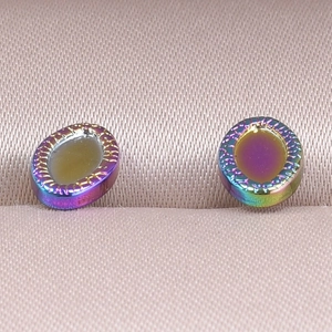 Macro detail of rainbow plated heart base stainless steel earrings on purple satin