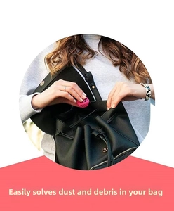 Internal view of a pink sticky cleaning ball picking up dirt inside a black leather bag