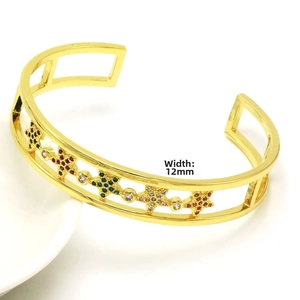 Detail of 12mm wide gold open cuff bracelet with colorful zircon stars on white porcelain