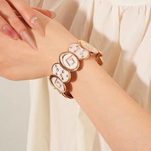 Détail du bracelet vintage doré avec émail blanc, motifs d'étoiles et un charm en forme de G