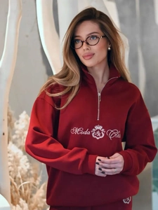 Detailed view of the Moda Club crown embroidery on a burgundy half-zip sweatshirt