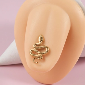 Close-up of golden snake tongue ring piercing on flesh-colored silicone model ear