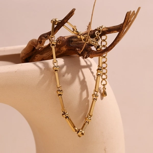 Detail of gold chain bracelet with paperclip links on a decorative wood branch