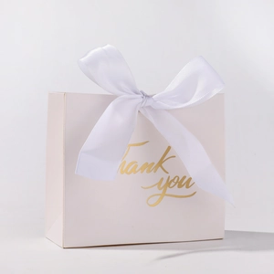 Detail of elegant white gift box with golden Thank You text and large white satin bow