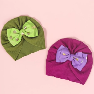 Detail of baby turban hats featuring double-layered bows and gold foil polka dot texture
