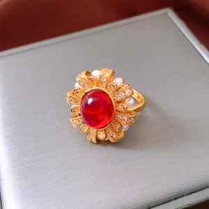 Detail of vintage 24k gold-plated ring with red oval stone, pearls and sun pattern