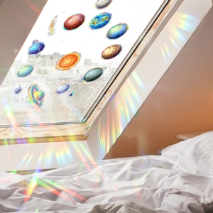 Rainbow prism window film showing planet decals casting vibrant colors on a bedroom wall