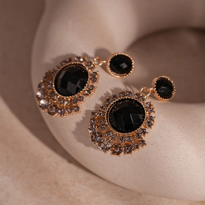 Detail of vintage gold sunflower earrings with black faceted gemstones and grey crystals