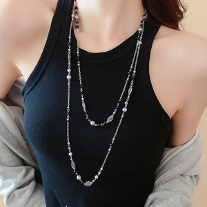 Detail of double-layer pearl necklace with floral pendant on model with black vest