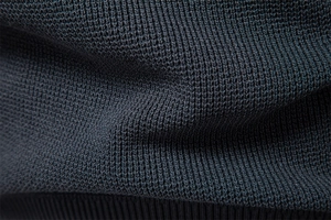 Macro view showing the dense knit texture and ribbed hem of a premium navy blue sweater