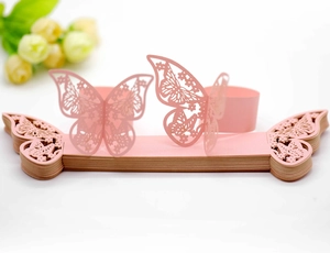 Detailed laser-cut hollow butterfly napkin rings in elegant pink paper for wedding decor