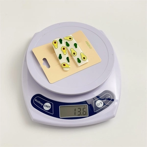 Detailed view of sweet fruit hair clips weighing 13.6g on a digital scale