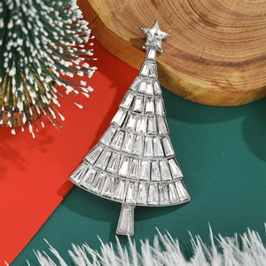 Macro shot of sparkling crystal Christmas tree brooch with star top on festive background