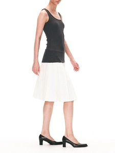 Side view of white pleated midi skirt paired with grey ribbed tank top on model