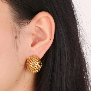 Close-up of golden hollow mesh spherical earring on ear showcasing retro French style