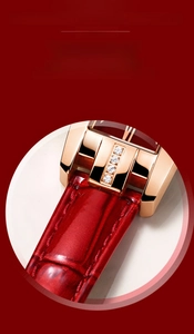Detail view of red crocodile-pattern leather strap with crystal-set rose gold buckle