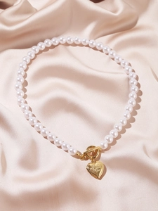 Detail of multi-layer baroque pearl necklace with golden heart toggle clasp and engraving