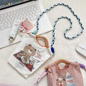 Détail d'ours brodé sur petit sac en toile avec bandoulière tressée colorée