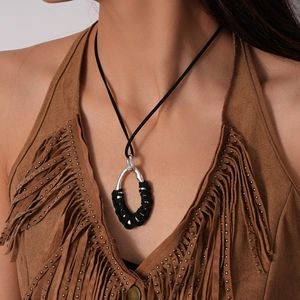 Detail of silver oval pendant with black woven thread on a bohemian style necklace