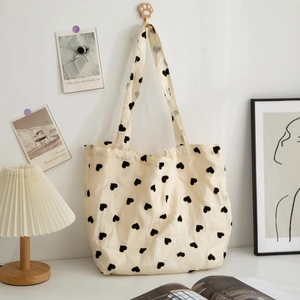 Large capacity cream canvas tote bag with black heart print and textured fabric finish.
