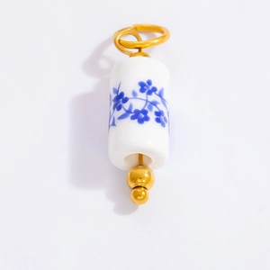 Macro detail of cylindrical blue and white porcelain pendant with gold metal accents