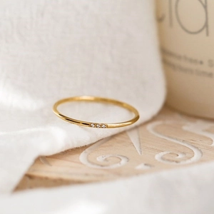 Details eines minimalistischen Gold-Zirkon-Rings auf einem Holztablett mit Naturlicht