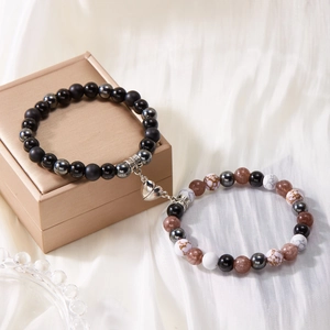 Close-up of heart-shaped magnetic clasp connecting natural stone beaded bracelets on silk