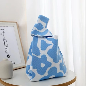 Close-up of a blue and white floral knit tote bag with a unique knotted handle design