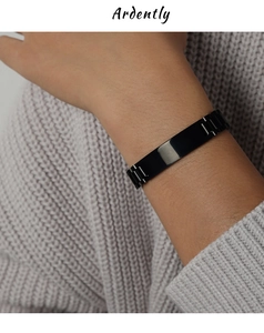 Macro detail of black metal link bracelet with a polished rectangle bar on wrist