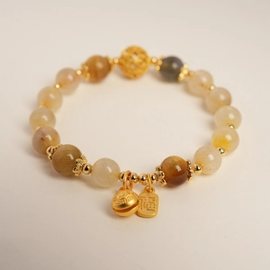 Détail d'un bracelet en perles de citrine avec pendentif Fu doré et clochette