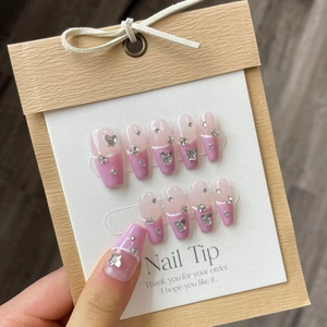 Close-up of pink French press-on nails with silver metal butterfly and crystal accents