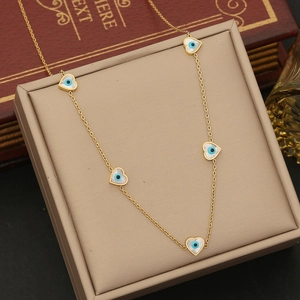 Detail of gold heart charms with blue evil eye inlay on a stainless steel chain necklace