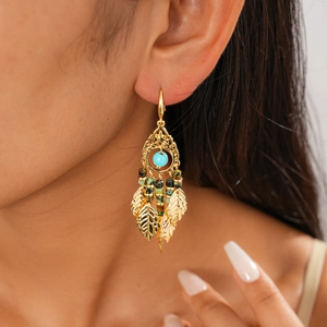 Gros plan détaillé de boucles d'oreilles dorées avec pierre turquoise et glands