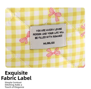 Close-up of yellow checkered quilted fabric with bow pattern and woven brand label