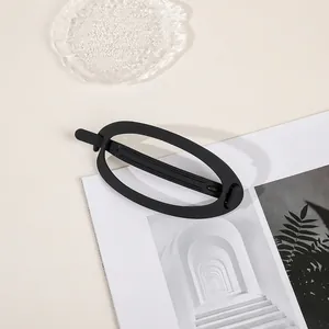 Detail view of a large matte black hollow oval hair claw clip on a minimalist desk