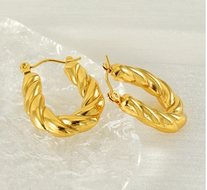 Macro shot of gold twisted hoop earrings showing polished texture and hinge closure