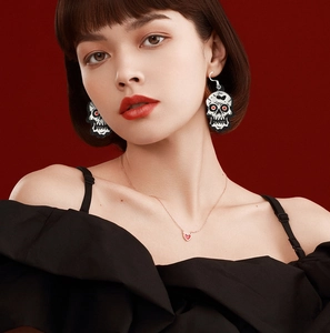 Close-up of skeleton drop earrings and red heart necklace on model for Halloween party