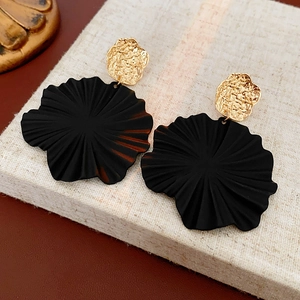 Detail shot of golden textured metal studs with large matte black flower charms on linen
