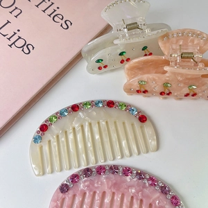 Detailed close-up of acetate hair combs and cherry claw clips with colorful rhinestones