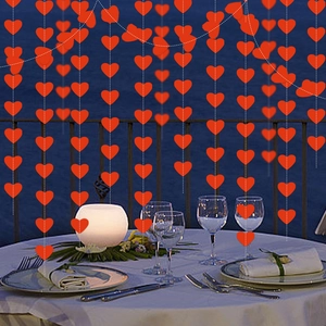 Red glitter heart garlands hanging above a romantic seaside dinner table setting