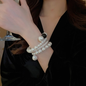 Detail of elegant multilayer pearl bracelet with a large black bead on a female wrist