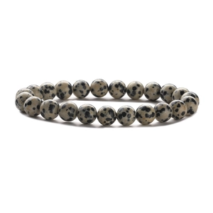 Detailed view of polished black and white spotted stone beads on a stretch bracelet