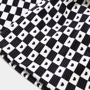 Close-up of checkerboard knit beanie with heart pattern and ribbed texture details