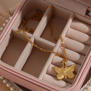 Elegant gold butterfly pendant necklace with twisted chain on pink jewelry box