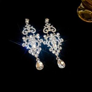 Detail of silver chandelier drop earrings with sparkling teardrop crystals on black background