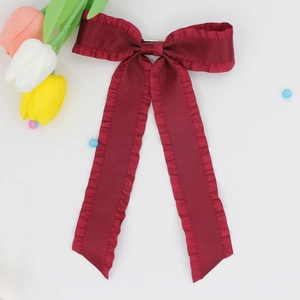 Detail of the pleated burgundy satin bow hair clip with elegant ruffles and vintage texture