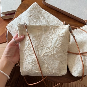 Artistic cream cotton linen crossbody bag featuring elegant floral leaf embroidery